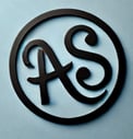Alex Schlumpf's logo, his initials in cursive: "AS"